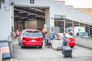 People unload items from red cars in a loading dock.