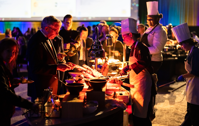 Chefs carving meat under warm lighting.