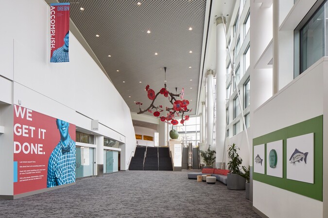 Glass floral sculptures line a bright building concourse.