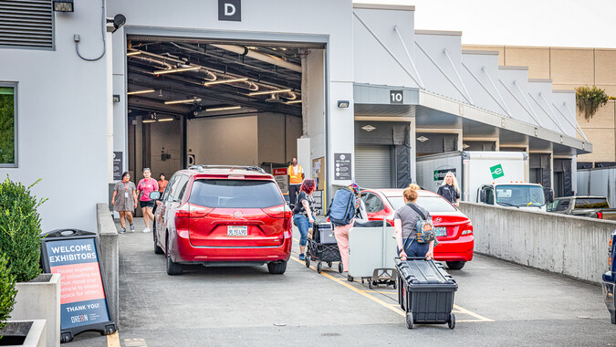 People unload items from red cars in a loading dock.
