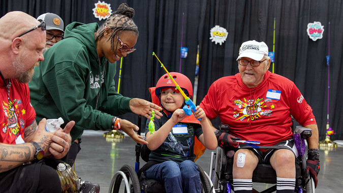 A young boy in a wheelchair plays a fun fishing game.