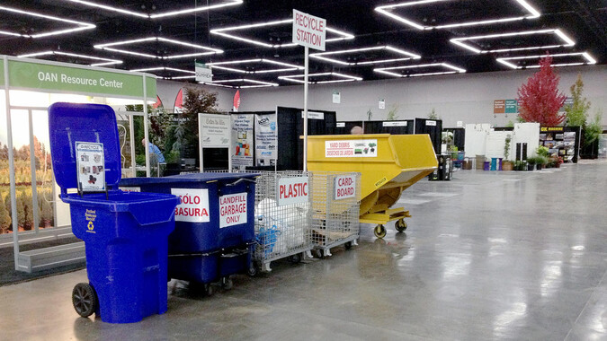 Colorful recycling containers neatly arranged inside a large exhibit hall.