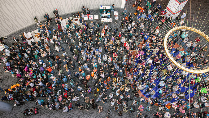 A birds eye view of hundreds of event guests in a large building lobby.