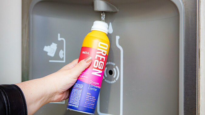 A colorful water bottle being filled at a water station. 