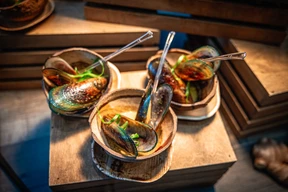 Three bowls of mussels garnished with greens.