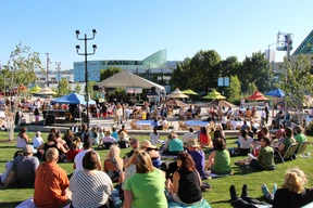 People seated on a grassy hill in a plaza.